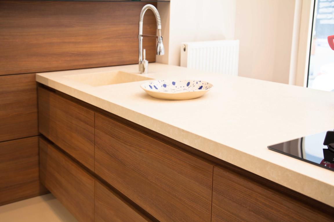 walnut cabinets in kitchen with light beige countertops and sink with plate on counter